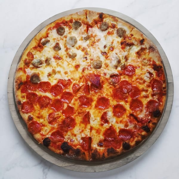 A half pepperoni, half sausage pizza on a wooden board, viewed from directly above.